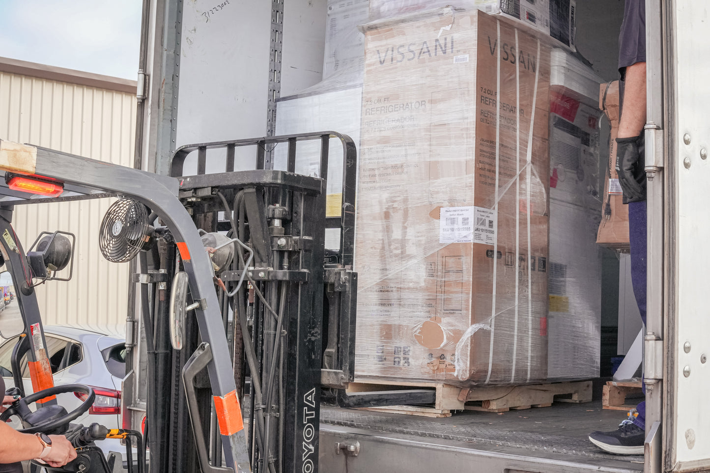 Person using a forklift to unload large Vissani boxes from a truck.
