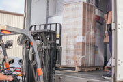 Person using a forklift to unload large Vissani boxes from a truck.