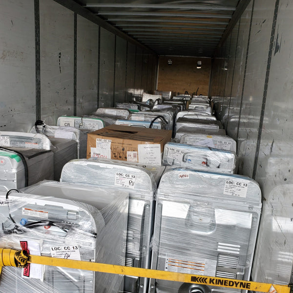 Pictured is a wholesale truckload of laundry appliances, primarily including washers and dryers.